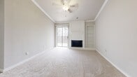 This single-story, 2-bedroom, 1-bathroom residence offers a thoughtfully designed open-concept layout that maximizes every square foot of its compact footprint. The living room serves as the heart of the home, featuring plush carpeting, crown molding, a ceiling fan, and a striking white brick fireplace flanked by built-in shelving. A sliding glass door floods the space with natural light and provides access to an outdoor area. The living room flows seamlessly into the dining area, where light wood-look flooring transitions to the kitchen. The kitchen is appointed with white cabinetry, a mosaic tile backsplash, granite countertops, stainless steel appliances including a refrigerator and range, and a convenient breakfast bar that opens to the dining space. A hallway leads to the two carpeted bedrooms, both finished in neutral tones. The primary bedroom is generously sized and features a walk-in closet outfitted with multi-tiered white shelving and hanging rods. The shared full bathroom includes a tub-shower combination with white tile surround, a granite-topped vanity, and wood-look flooring. Throughout the residence, a consistent neutral palette and clean finishes create a cohesive and functional living environment.