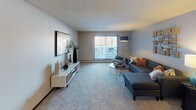 This single-floor residence offers a thoughtfully designed layout with two bedrooms, multiple bathrooms, a dedicated dining area, and a generous living room. The living room is carpeted and bathed in natural light through a large window fitted with vertical blinds, creating a bright and open atmosphere. A galley-style kitchen features rich dark cabinetry, granite-look countertops, hardwood-style flooring, a stainless steel refrigerator, and ample storage, including a pantry closet.

The dining area sits adjacent to the kitchen, accented by hardwood-style flooring and wall art. The primary bedroom is carpeted and spacious, offering a ceiling fan, a window with natural light, and direct access to a bathroom with a granite vanity and a walk-in closet equipped with built-in shelving. A second bedroom also features plush carpeting, a large sliding-door closet, and a window with outdoor views. An additional bathroom includes tile flooring, a dark vanity, and a tub-shower combination. Throughout the unit, dark wood accents and neutral gray tones create a cohesive, contemporary aesthetic.
