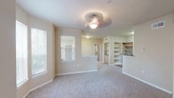 This classic 2-bedroom, 2-bathroom residence is thoughtfully laid out across a single floor, offering a comfortable and functional living environment. The open living and dining area is carpeted and bathed in natural light from multiple windows with blinds, and features a ceiling fan/light fixture overhead. A half-wall partition separates the living space from the kitchen area, which is equipped with light wood cabinetry, dark laminate countertops, a coil-top electric range, over-the-range microwave, and a dishwasher. Built-in shelving units provide convenient storage adjacent to the kitchen. A glass door in the living area leads to an outdoor space, further enhancing the sense of openness. Both bedrooms are generously sized, carpeted, and include ceiling fans and windows that invite natural light. The primary bedroom features a walk-in closet and an en-suite bathroom with a double-sink vanity, light wood cabinetry, dark countertops, a large mirror, and a tub/shower combo with white tile surround. The second bathroom also includes a tub/shower combo. A dedicated utility area with wood-look flooring houses the water heater and electrical panel, adding practical convenience to the layout.