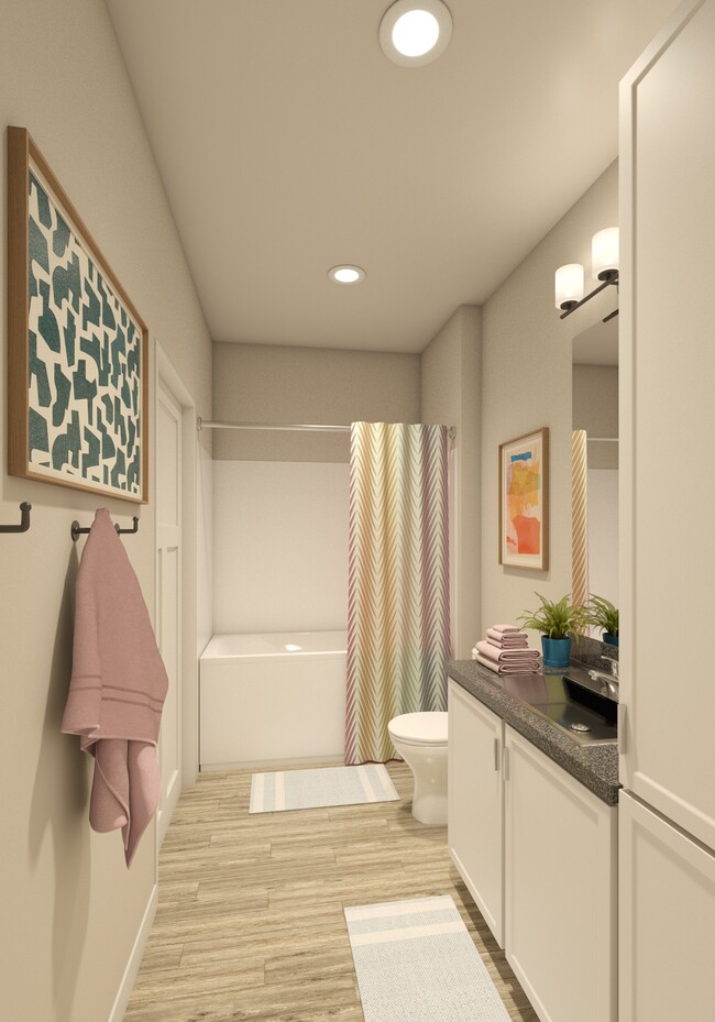Baño de un apartamento en Greenwood Commons que muestra un lavabo, espejo, bañera e iluminación de techo. - Greenwood Commons Apartments