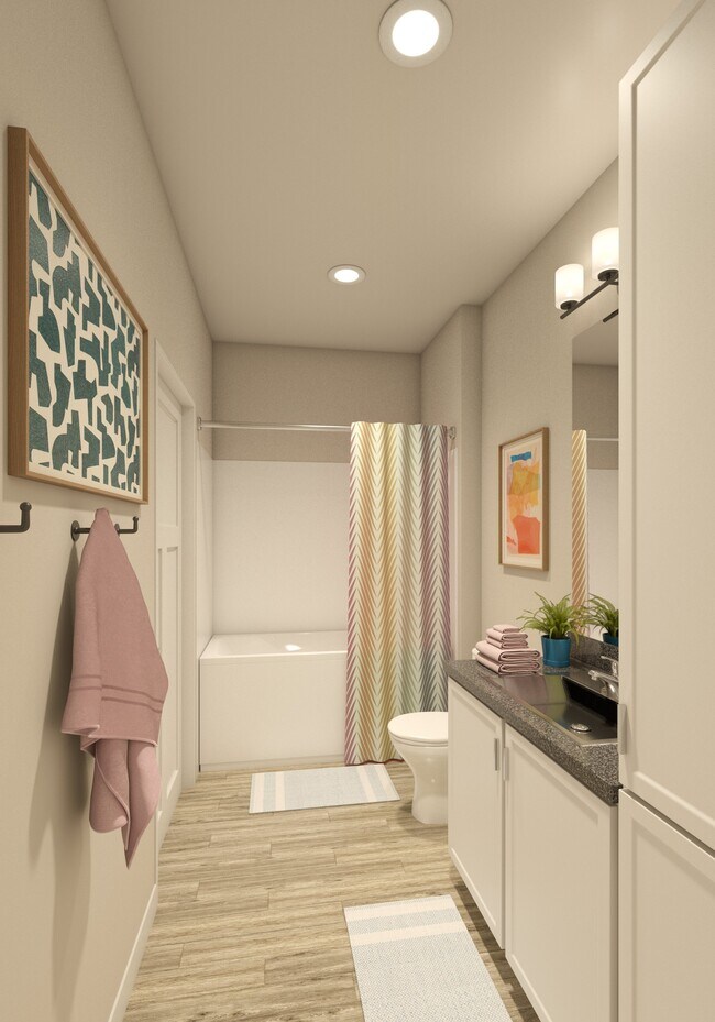 Greenwood Commons apartment bathroom showing a sink, mirror, bathtub, and overhead lighting. - Greenwood Commons Apartments