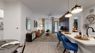 This single-story residence features two bedrooms and two bathrooms across a thoughtfully designed floor plan. The open-concept living, dining, and kitchen area forms the heart of the home, anchored by light wood-tone flooring that flows throughout. The living room makes a bold statement with a striking navy and rust plaid feature wall serving as a backdrop for the media console, while large windows with linen drapes and a ceiling fan invite abundant natural light. A cozy seating arrangement and an artfully layered area rug complete the space.

The kitchen is finished with dark, textured cabinetry, white quartz countertops, stainless steel appliances, and a black matte faucet, with a built-in geometric wine rack adding a decorative touch. The dining area accommodates a round table with bench seating and is accented by a curated gallery wall.

The spacious primary bedroom features a geometric patterned accent wall, large windows, a ceiling fan, and direct access to an ensuite bathroom with a double vanity, dark cabinetry, and a glass-enclosed walk-in shower. The second bedroom is bright and airy, bathed in natural light. A hallway and dedicated closet provide additional storage throughout.