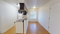 This single-floor 1-bedroom, 1-bathroom unit offers a practical and comfortable layout with clean finishes throughout. The kitchen is a standout feature, equipped with dark espresso cabinetry extending to the upper walls, a gas range, refrigerator, built-in microwave, and a stainless steel sink set into a continuous countertop. Light hardwood-style flooring runs through the kitchen and living area, while a window with blinds allows natural light to brighten the space. The kitchen flows openly into the adjacent dining or living area, creating a cohesive, easy-to-navigate floor plan. The bedroom is generously sized, featuring plush carpeting, a ceiling fan with integrated lighting, and a window with blinds that invites natural light. A closet is conveniently located just off the bedroom, offering dedicated storage space. The bathroom is accessible directly from the bedroom area and features dark vanity cabinetry, a mirror, and a full tub-and-shower combination with white subway-style wall tiling and chrome fixtures. Throughout the unit, neutral wall tones and textured ceilings contribute to a clean, move-in-ready aesthetic.