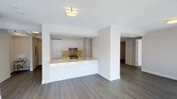 This 2-bedroom, 3-bathroom residence is designed with a clean, contemporary aesthetic that emphasizes open living and refined finishes. Wide-plank hardwood floors in a warm gray tone extend throughout the space, creating a cohesive and sophisticated foundation.

The kitchen is a standout feature, showcasing high-gloss white cabinetry that reaches toward the ceiling, complemented by a striking stone mosaic backsplash in warm gold and brown tones. A generous peninsula with a light-toned stone countertop provides ample prep space and serves as a natural divider between the kitchen and the open living area. Gold-toned fixtures, including the kitchen faucet, add a refined, modern touch. Recessed lighting within the kitchen, paired with a flush-mount ceiling fixture in the living area, ensures well-distributed illumination throughout.

The open-concept layout connects the kitchen and living spaces seamlessly, offering a sense of spaciousness and ease of flow. Clean white walls and smooth ceilings maintain a bright, airy atmosphere. The thoughtful layout continues into the private quarters, with hallways leading to the bedrooms and three well-appointed bathrooms. The overall ambiance is modern, understated, and move-in ready, ideal for those seeking a polished and functional living environment.