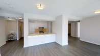 This 2-bedroom, 3-bathroom residence is designed with a clean, contemporary aesthetic that emphasizes open living and refined finishes. Wide-plank hardwood floors in a warm gray tone extend throughout the space, creating a cohesive and sophisticated foundation.

The kitchen is a standout feature, showcasing high-gloss white cabinetry that reaches toward the ceiling, complemented by a striking stone mosaic backsplash in warm gold and brown tones. A generous peninsula with a light-toned stone countertop provides ample prep space and serves as a natural divider between the kitchen and the open living area. Gold-toned fixtures, including the kitchen faucet, add a refined, modern touch. Recessed lighting within the kitchen, paired with a flush-mount ceiling fixture in the living area, ensures well-distributed illumination throughout.

The open-concept layout connects the kitchen and living spaces seamlessly, offering a sense of spaciousness and ease of flow. Clean white walls and smooth ceilings maintain a bright, airy atmosphere. The thoughtful layout continues into the private quarters, with hallways leading to the bedrooms and three well-appointed bathrooms. The overall ambiance is modern, understated, and move-in ready, ideal for those seeking a polished and functional living environment.