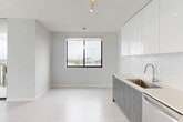 Located at 150 S Bryan Rd in Dania Beach, Florida, this three-bedroom, two-bathroom residence offers a well-designed single-floor layout with a clean, contemporary aesthetic throughout. Light wood-style flooring flows seamlessly across all rooms, complemented by crisp white walls and modern finishes that create a bright, airy atmosphere.

The kitchen is a standout feature, showcasing high-gloss white upper cabinetry, wood-toned lower cabinets, a subway tile backsplash, light quartz countertops, and a full suite of stainless steel appliances including a range, microwave, dishwasher, and French door refrigerator. Track lighting overhead adds a modern touch. The kitchen opens directly to a hallway and living area, promoting an open, connected feel.

Each of the three bedrooms is well-proportioned and filled with natural light through large windows framing expansive views of the Dania Beach skyline and lush treetops. The bedrooms feature double-door closets with sleek black hardware, adding a refined contrast to the otherwise all-white palette.

The two bathrooms are finished with neutral tile, modern vanities with wood-toned cabinetry, and a tub-shower combination with tile surround. Clean lines and recessed lighting maintain the contemporary feel throughout. Two hallways connect the rooms efficiently, and a dedicated closet provides additional storage.