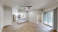 This single-floor unit offers an efficiently organized layout that maximizes every square foot of its living space. The open-concept kitchen and living room serves as the heart of the unit, where warm wood-look flooring, neutral gray walls, and a textured ceiling create a clean, modern aesthetic. A ceiling fan anchors the living area, which benefits from natural light streaming through a sliding glass door that opens to a private outdoor balcony, as well as an additional window along the adjoining wall.

The kitchen is well-appointed with white shaker-style cabinetry, a classic subway tile backsplash, and stainless steel appliances including a refrigerator, range, and built-in microwave. A peninsula with a white quartz countertop and undermount sink provides both additional prep space and a casual dining option, seamlessly connecting the kitchen to the living area. An adjacent pantry offers convenient open shelving for extra storage.

The bathroom features a full tub and shower combo with clean white tile surround and brushed nickel fixtures. A dedicated laundry area and a closet round out the unit's functional offerings. Throughout the space, consistent flooring, bright white trim, and a cohesive neutral palette contribute to a tidy and inviting atmosphere.