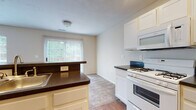 Located at 6345 Cooper Rd in Columbus, Ohio, this two-story home offers a well-organized layout across two levels. The kitchen is equipped with white cabinetry, dark countertops, a gas range, built-in microwave, and a refrigerator. Recessed lighting and hardwood-style flooring give the kitchen a clean, practical feel, while a peninsula with a sink provides additional workspace and an open connection to adjacent areas. A large window with vertical blinds allows natural light to pour into the kitchen and dining space, with views of surrounding greenery.

The main living area features plush carpeting, neutral-toned walls, and a staircase leading to the upper level. Upstairs, a standout room showcases vaulted ceilings, a ceiling fan, and an arched window that fills the space with natural light and outdoor views, creating an airy and open atmosphere.

Bedrooms are carpeted and well-lit by windows overlooking the surrounding trees. The home includes multiple bathrooms: a full bath with a tub-shower combination and wood-look flooring, a second full bath with a standalone shower and warm hardwood flooring, and a half bath with tile flooring and a white vanity. Each bathroom is finished with white fixtures and ample mirror and storage space.