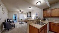 Located at 513 Dodson Rd in Rogers, Arkansas, this single-floor residence offers a well-designed, functional layout with a warm and comfortable ambiance throughout. The open-concept kitchen flows seamlessly into the living area, creating a connected and sociable space. The kitchen is equipped with warm-toned wood cabinetry, a double-basin sink, tile flooring, and includes a full suite of white appliances—including a range, over-the-range microwave, and dishwasher—providing ample storage and counter space. The living room features plush carpeting, a ceiling fan, and room for multiple seating arrangements, with natural light filtering in through windowed curtained panels. A flex room with large windows and soft carpet offers versatility as a home office or additional living space. Both bedrooms are carpeted and include ceiling fans, generous closet access, and windows that bring in natural light. The bathroom features tile flooring, a wood-toned vanity with a large mirror, and a shower-tub combination. A dedicated in-unit laundry room houses a full-size washer and dryer on tile flooring, adding everyday convenience. Neutral tones and consistent finishes tie the space together throughout.