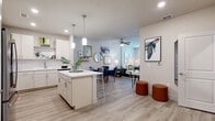 Located at 1155 Park Ln in Davenport, Florida, this single-story residence offers a thoughtfully designed open-concept layout that seamlessly connects the kitchen, dining, and living areas. Light wood-tone flooring flows throughout, creating a cohesive and airy atmosphere across the entire space.

The kitchen is a standout feature, equipped with stainless steel appliances including a refrigerator, range, microwave, and dishwasher. Crisp white subway tile backsplash, light wood cabinetry, quartz countertops, and a central island with pendant lighting complete the polished, modern aesthetic. The open layout allows the kitchen to flow naturally into the dining and living areas, which are brightened by recessed lighting and ceiling fans.

The living room provides a comfortable and inviting atmosphere, with light-filled interiors and ample wall space. The bedrooms are well-proportioned, each featuring large windows with sheer curtains that allow generous natural light, along with ceiling fans for added comfort. The primary bathroom offers a clean, spa-like design with a wide vanity, quartz countertop, walk-in glass shower, and an adjacent walk-in closet with built-in shelving. The overall ambiance of the home is bright, contemporary, and move-in ready.