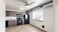 Located at 5910 S Graystone Ave in Sioux Falls, SD, this one-bedroom, one-bathroom unit offers a practical and well-organized layout across a single floor. Light wood-style flooring runs throughout the main living areas, lending a clean, cohesive look to the space.

The combined kitchen and dining area serves as the heart of the unit. The kitchen is outfitted with dark-toned cabinetry, light countertops, and a full suite of black appliances including a refrigerator, electric range, microwave, and dishwasher. Exposed ductwork runs along the ceiling, adding an industrial touch, while a ceiling fan and a window with blinds provide ventilation and natural light. A chandelier overhead enhances the dining area.

A hallway connects the main living space to the private areas of the unit. The bedroom is a well-proportioned room featuring light wood-style flooring, a ceiling fan, and clean white walls that create a calm, restful atmosphere.

The bathroom is noteworthy for its functionality, housing a full tub/shower combination alongside an in-unit washer and dryer — a convenient feature that adds practical value. Tile flooring and neutral gray walls complete the space.

Throughout the unit, textured ceilings, consistent flooring, and a neutral color palette contribute to a tidy and functional living environment.