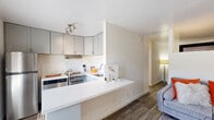 Located at 710 South Hardy Drive in Tempe, Arizona, this single-floor, 2-bedroom, 1-bathroom unit offers a smartly designed layout that maximizes every inch of its compact footprint. The open-concept kitchen is a standout feature, outfitted with sleek grey upper cabinetry, stainless steel appliances including a full-size refrigerator and range, a built-in under-cabinet range hood, and a crisp white peninsula countertop that doubles as a breakfast bar and provides a seamless visual connection to the living area. Wood-look plank flooring runs throughout the main living spaces, adding warmth and cohesion to the bright, neutral color palette. The living room flows naturally from the kitchen, creating a comfortable and functional common area. Both bedrooms are intimate yet well-proportioned, with clean white walls and the same wood-look flooring, offering a cozy and restful atmosphere. The primary bedroom provides enough space for a queen-sized bed and additional furnishings. A dedicated closet provides convenient storage. The bathroom features a full tub-shower combination with white tile surround and modern brushed nickel fixtures, maintaining the clean aesthetic found throughout the unit. Overall, the space presents a cohesive, modern design well-suited for efficient urban living in the heart of Tempe.