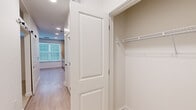 Located at 440 N Monroe St in Tallahassee, FL, this one-bedroom, one-bathroom unit offers a well-planned layout that maximizes every square foot across a single floor. The open kitchen is a standout feature, showcasing light wood cabinetry with sleek hardware, a white subway tile backsplash, stainless steel appliances including a refrigerator, range, microwave, and dishwasher, and light wood-look flooring that extends throughout the main living areas. Recessed lighting and large windows with blinds allow natural light to fill the space. A hallway connects the kitchen and living area to the private quarters, lined with panel-style doors accented by black hardware for a modern touch. The bedroom features neutral carpet flooring, soft grey walls, and a ceiling fan, creating a calm and restful atmosphere. A dedicated closet with built-in shelving provides practical storage. The bathroom offers a clean, all-white tiled walk-in shower enclosed by a frameless glass door with matte black hardware, lending a contemporary feel. The overall design is cohesive, with a neutral color palette, modern fixtures, and efficient use of space throughout.