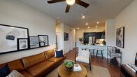 This single-story residence in Houston's Lincoln Heights neighborhood showcases a thoughtfully designed open-concept layout that seamlessly connects the living, dining, and kitchen areas. Rich hardwood-style flooring runs throughout the main living spaces, complemented by recessed lighting and ceiling fans that enhance the bright, welcoming atmosphere.

The kitchen is a standout feature, equipped with dark espresso cabinetry, stainless steel appliances including a full-size refrigerator, electric range, microwave, and dishwasher. A generous white quartz peninsula with bar seating provides ample prep space and casual dining options, making it ideal for entertaining.

The living area offers a comfortable and cohesive space, with a ceiling fan overhead and natural light filtering in from nearby windows. The bedroom continues the modern aesthetic with soft carpet flooring, a ceiling fan, and well-sized windows dressed with blinds and curtains that allow for adjustable natural light and privacy.

The bathroom is sleek and functional, featuring dark cabinetry, a long vanity with light countertops, hardwood-style flooring, and a walk-in closet with built-in shelving and hanging rods, providing excellent storage throughout.