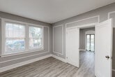 Located at 5345 Cabanne Ave in St. Louis, MO, this 3-bedroom, 1-bathroom residence offers a thoughtfully designed single-floor layout. The unit is finished with light hardwood-style flooring throughout, paired with neutral gray walls and crisp white trim and baseboards, creating a clean, cohesive aesthetic in every room.

The living area makes a strong first impression with an arched entryway, decorative wall molding panels, and an arched front door that adds architectural character. Multiple windows flood the space with natural light and provide views of the surrounding greenery, contributing to an airy, open ambiance.

The galley-style kitchen is well-appointed with gray shaker cabinets, granite-look countertops, a tile backsplash, and black appliances including a gas range and full-size refrigerator. A window above the sink brings in additional natural light.

The primary bedroom is generously sized, featuring an arched window, a standard window, and a sliding glass door that opens to the outdoors. The additional bedrooms are comfortably proportioned, each with closet access and neutral finishes. A central hallway connects the bedrooms to the shared full bathroom, which includes a vanity with a white countertop. The layout is efficient and functional, making excellent use of the available space.
