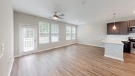 This well-designed two-story home offers a thoughtful layout with contemporary finishes across both levels. The main floor features an open-concept living area with wood-look plank flooring, neutral gray walls, and a ceiling fan, creating a bright and airy atmosphere. Natural light flows in through multiple windows, enhancing the clean, modern aesthetic throughout.

The kitchen is a standout feature, showcasing slate-gray shaker-style cabinetry with brushed nickel hardware, light quartz countertops, a classic white subway tile backsplash, and a full suite of stainless steel appliances including a range, microwave, and refrigerator. A peninsula with pendant lighting provides additional prep space and casual dining. A half bathroom on the main level features matching gray cabinetry with a white vanity top and wood-look flooring.

Upstairs, the bedrooms are carpeted for comfort and receive generous natural light through large windows with blinds. The upper-level bathrooms mirror the home's consistent design language, featuring gray vanity cabinetry, white countertops, and wood-look plank flooring. The primary bathroom includes a glass-enclosed walk-in shower with tiled walls. A staircase connects both floors, completing this cohesive and move-in ready home.