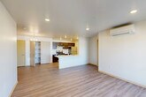 This single-floor, 3-bedroom, 2-bathroom unit offers a thoughtfully designed layout that maximizes functionality and comfort. The open-concept living and kitchen area serves as the heart of the home, featuring light wood-tone luxury vinyl plank flooring, recessed lighting, and a wall-mounted mini-split air conditioning unit. A peninsula with a white countertop and integrated sink anchors the kitchen, which is equipped with dark espresso cabinetry, a stainless steel refrigerator, an electric range, and a range hood. A dedicated closet provides additional pantry or storage space just off the kitchen. French doors in the living area flood the space with natural light and provide outdoor access, complemented by a secondary entry door. The bedrooms are carpeted for added comfort, with the primary bedroom featuring a ceiling fan, a large window with outdoor views, and a baseboard heater. The primary bathroom includes a white countertop vanity, wood-toned cabinetry, a bathtub with shower, and direct access to a dedicated walk-in closet. A second bathroom offers similar finishes and includes an in-unit washer and dryer, adding everyday convenience. The unit's clean, neutral palette and consistent flooring create a cohesive, modern aesthetic throughout.