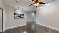 Located at 508 N College Ave in Bloomington, Indiana, this spacious 5-bedroom, 2-bathroom single-floor unit offers a well-designed layout suited for shared or family living. The open-concept living and kitchen area serves as the heart of the home, showcasing polished concrete floors that run throughout and contribute a sleek, modern industrial aesthetic. The kitchen features dark espresso cabinetry, granite-style countertops, a breakfast bar with seating, pendant lighting, and stainless steel appliances including a refrigerator, microwave, and range. Track lighting and a ceiling fan complete the living area, which offers ample room to relax and entertain. Five generously sized bedrooms provide comfortable personal spaces, with the primary bedroom offering a notably spacious footprint. Several bedrooms benefit from multiple windows that invite natural light. A dedicated closet with wire shelving adds practical storage. The two bathrooms are finished with dark vanity cabinetry, white countertops, large mirrors, and glass-enclosed showers with polished tile flooring. Neutral warm-gray walls and clean white baseboards tie the interior together with a cohesive, contemporary feel throughout this well-appointed Bloomington residence.