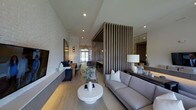 This thoughtfully designed single-floor residence showcases a refined modern aesthetic, where clean lines and carefully selected materials come together to create a cohesive and sophisticated atmosphere. The open-concept layout connects the living, dining, and entertaining areas in a seamless flow, offering a sense of spaciousness and versatility. Light-toned hardwood flooring runs throughout, complementing the neutral color palette that defines the interior. A striking vertical wood slat partition serves as a stylish architectural divider, adding visual depth and texture while maintaining an open feel between spaces. The living area is anchored by a plush gray sofa, a sculptural round white coffee table, and a console table with decorative accents, all set against a beautifully textured stone feature wall. Recessed lighting illuminates the interiors alongside warm pendant fixtures that add character. Natural light pours in through large windows at the far end of the space, brightening the dining area and highlighting the home's airy ambiance. A large mirror near the seating area enhances the sense of openness. Every element of this space reflects a commitment to contemporary design, balancing comfort and style in a polished, move-in-ready environment.