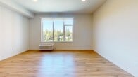 Located at 13155 SW 68th Pkwy in Tigard, Oregon, this well-designed 2-bedroom, 2-bathroom unit offers a clean, modern aesthetic across a single floor. Light-toned hardwood-style flooring runs throughout the entire space, creating a cohesive and bright atmosphere in every room.

The open-concept kitchen and living area serves as the centerpiece of the unit. The kitchen is outfitted with warm wood-grain cabinetry, a teal subway tile backsplash, stainless steel appliances including a French door refrigerator, microwave, and range, and a sleek white countertop island with pendant lighting above — ideal for both cooking and casual dining.

The primary bedroom is a comfortable size and features a large window with views of surrounding greenery, filling the room with natural light. It is complemented by a dedicated walk-in closet equipped with wire shelving and hanging rails for ample storage. The second bedroom is well-proportioned with clean white walls and the same warm flooring.

Both bathrooms maintain a consistent modern design, each featuring a soaking tub and shower combination, a wood-tone vanity with a white countertop, and a large mirror. The layout is efficient and functional throughout. Two closets provide generous storage across the unit.
