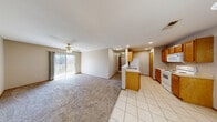 Located at 2650 N Barnes Ave in Springfield, Missouri, this single-story, three-bedroom, two-bathroom home offers a functional and well-organized layout. The open-concept living area seamlessly connects the kitchen, dining, and living spaces. The kitchen features warm honey-toned wood cabinetry, white appliances including an electric range, microwave, refrigerator, and dishwasher, complemented by tile flooring and a central island with a sink. An elegant chandelier anchors the dining area, while the living room is finished with plush carpet, recessed lighting, and a ceiling fan. A sliding glass door floods the living space with natural light and provides access to an outdoor balcony or patio. A carpeted hallway with a utility panel connects the bedrooms, each finished with carpet flooring, ceiling fans, and natural light from windows. The primary bedroom includes closet space with wire shelving systems for practical organization. The bathrooms offer standard tub-shower combinations. Additional spaces include a laundry area, pantry, utility room, and multiple closets, ensuring ample storage throughout the home.