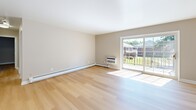 Located at 300 Glen Meadow Rd in Franklin, MA, this two-bedroom, one-bathroom residence offers a well-organized single-floor layout designed for comfortable everyday living. Light-toned hardwood flooring runs consistently throughout, creating a cohesive and clean aesthetic across every room.

The living room is generously proportioned, bathed in natural light from a large sliding glass door that opens to an outdoor view of the surrounding community. A wall-mounted HVAC unit and baseboard heating ensure year-round comfort. The space flows naturally into the hallway, which connects all rooms efficiently.

The kitchen features warm oak cabinetry with ample upper and lower storage, granite-patterned countertops, a stainless steel sink, and a stainless steel dishwasher — all set atop the same light hardwood flooring found throughout the unit.

The primary bedroom is notably spacious, highlighted by three windows that fill the room with natural light and baseboard heating along the wall. The second bedroom is equally inviting, with a large window overlooking greenery, a full-width louvered closet, and baseboard heating.

The bathroom includes a full tub-shower combination with white tile surround, chrome fixtures, and classic stone-look tile flooring. Neutral warm-beige walls and clean white trim throughout tie the entire residence together with a calm, move-in-ready presentation.