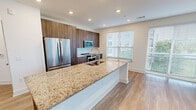 Located at 360 Village Dr in King of Prussia, PA, this well-appointed 2-bedroom, 3-bathroom residence offers a thoughtfully designed single-floor layout with contemporary finishes throughout. Light wood-tone flooring runs throughout the home, complementing the neutral, warm wall tones that lend a clean and modern aesthetic.

The open-concept kitchen and living area serves as the heart of the home. The kitchen features rich dark wood cabinetry, a granite-topped island with an undermount sink, stainless steel appliances including a French door refrigerator, microwave, and range, plus a bright window that fills the space with natural light.

The expansive living room is bathed in natural light through large floor-to-ceiling windows and sliding glass doors that offer views of lush greenery outside.

The bedrooms are comfortably sized and bright, each benefiting from windows with outdoor views. The primary bedroom includes access to a well-designed en-suite bathroom with granite countertops, dark wood vanity cabinetry, a large framed mirror, and a glass-enclosed walk-in shower. A second bathroom features elegant marble-style tile surrounding a soaking tub and shower combination. Multiple closets with wire shelving systems provide ample storage throughout.

A dedicated in-unit laundry closet houses a full-size Whirlpool front-load washer and dryer, adding everyday convenience to this polished, move-in-ready home.