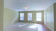 Located at 190 Penny Lane in Powell, Ohio, this single-floor property offers a comfortable and well-lit living environment designed with both functionality and style in mind. The interior is finished in soft, neutral green tones that create a calm and welcoming atmosphere throughout the space.

The main living area is generously sized and bathed in natural light, courtesy of multiple large windows fitted with white blinds that allow for flexible light control. The windows face outward to a lush exterior, inviting the outdoors in and enhancing the airy feel of the room. The combination of plush carpeting and hardwood flooring adds both warmth and practicality, with carpet providing comfort in the main gathering area and hardwood offering a durable, easy-to-maintain surface along the edges.

Ceiling-mounted lighting provides consistent illumination throughout, complementing the abundant natural light. Clean white baseboards and ceilings contrast neatly with the sage-green walls, lending a fresh and polished look to the interior. The overall design reflects a straightforward, move-in-ready aesthetic that is both practical and inviting — well-suited for everyday living in the desirable Powell, Ohio community.