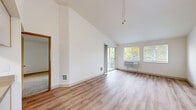 This single-floor residence offers three bedrooms, two bathrooms, and a thoughtfully organized layout across a comfortable footprint. The living room immediately impresses with its dramatic vaulted ceilings and light wood-style flooring, creating an open and airy atmosphere. Large sliding glass doors lead to a private balcony overlooking a lush, tree-lined outdoor area, while additional windows flood the space with natural light. A ceiling fan adds to the comfort of the living area, which flows conveniently toward the kitchen. The kitchen is well-equipped with ample cream-colored cabinetry, wood-trimmed accents, generous countertop space, and white appliances including a refrigerator, electric range, and dishwasher. A dedicated laundry area adds practical convenience. The hallways connect to three carpeted bedrooms, each offering a calm retreat with neutral tones and natural light. The primary bedroom is generously sized and includes a sliding-door closet. The two bathrooms are clean and functional, each featuring a tub-shower combination, vanity with countertop sink, and light wood-style flooring. With seven closets distributed throughout, storage is plentiful. The overall aesthetic is bright, clean, and practical, suited for comfortable everyday living.