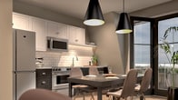 This 450 square foot apartment in Elkhart, IN, maximizes space efficiency with a thoughtful layout. The single bedroom, measuring 130 square feet, features a large window providing ample natural light and urban views. The room is furnished with a queen-sized bed, complemented by a neutral color palette and textured bedding.

The living area showcases an open-concept design, seamlessly blending with the kitchen. A comfortable sofa adorned with an array of throw pillows faces a striking abstract wall art, creating a focal point in the room. The kitchen, while compact, is well-equipped with modern stainless steel appliances, including a four-door refrigerator. White cabinetry and subway tile backsplash contribute to a clean, contemporary aesthetic.

Throughout the apartment, light wood flooring adds warmth and continuity. The sloped ceiling in the bedroom and kitchen areas adds architectural interest and a sense of height to the space. Large windows in both the bedroom and living area flood the apartment with natural light and offer views of the surrounding cityscape.

The bathroom, though not pictured, completes this efficient one-floor layout. Despite its modest 450 square foot size, the apartment's clever design and modern furnishings create a spacious feel, making it an ideal urban dwelling for singles or couples seeking a stylish, low-maintenance living space in downtown Elkhart.