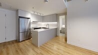 Located at 650 Wellington in Montréal's dynamic Griffintown neighbourhood, this well-appointed 2-bedroom, 2-bathroom unit offers a thoughtfully designed single-floor layout. Light hardwood flooring flows throughout the open-concept living areas, complemented by crisp white walls and striking exposed concrete ceilings and columns that lend an industrial character to the space.

The modern kitchen serves as a central hub, featuring a sleek island with an integrated sink, grey flat-panel cabinetry with under-cabinet lighting, a clean white backsplash, and stainless steel appliances — including a full-size refrigerator. The kitchen opens conveniently toward one of the bathrooms, enhancing the functional flow of the unit.

Both bedrooms are comfortably proportioned, with large black-framed windows that frame views of the surrounding urban streetscape and allow generous natural light to fill each room. The exposed concrete ceiling adds an architectural edge consistent throughout.

The two bathrooms are finished in a clean, contemporary style with white subway tile. One features a soaking bathtub with a handheld shower fixture, while the other offers a walk-in shower with floor-to-ceiling tile and modern chrome fixtures. Both spaces maintain a bright, spa-like aesthetic with light wood-tone flooring.