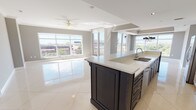 This well-appointed 2-bedroom, 2-bathroom residence is designed with an open, flowing layout across a single floor. The heart of the home is a striking open-concept kitchen and living area finished with large-format polished tile flooring that reflects abundant natural light. The kitchen features a substantial two-tone island with dark navy cabinetry topped with white quartz countertops, complemented by white upper cabinets with glass-front doors and stainless steel appliances. A dramatic multi-arm chandelier adds a decorative focal point to the dining area.

Floor-to-ceiling windows throughout the main living area flood the space with natural light and offer expansive elevated views of the surrounding cityscape and greenery. The living area includes a ceiling fan and tray ceiling detailing, adding architectural depth.

Both bedrooms are generously sized with plush carpeting, ceiling fans, large windows, and ample closet space with built-in shelving. One bedroom provides direct access to a private balcony with a decorative balustrade railing.

The two bathrooms are distinctly appointed: one features marble-surround walls, a soaking tub, and glass enclosure; the other offers a glass-enclosed walk-in shower, vanity, and polished tile flooring. Panel-style interior doors with brushed nickel hardware complete the refined aesthetic throughout.
