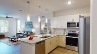 This well-designed single-floor residence offers a thoughtful layout that balances comfort and functionality. The open-concept kitchen serves as the heart of the home, featuring granite countertops, light wood cabinetry paired with crisp white upper cabinets, a subway tile backsplash, and a full suite of stainless steel appliances including a range, microwave, dishwasher, and refrigerator. A peninsula with seating provides additional prep space and a casual dining option, while pendant lighting adds a modern touch overhead.

The living area is bright and welcoming, with wood-style flooring, a ceiling fan, and large windows that invite natural light and outdoor views. A sliding door opens directly to a private balcony, extending the living space outdoors.

The primary bedroom is generously sized, featuring plush carpeting, a ceiling fan, and a large window overlooking greenery. A second bedroom offers a cozy, well-proportioned space with soft carpeting and ample room.

Two bathrooms serve the residence: one featuring a walk-in glass-enclosed shower with wood-style flooring and granite vanity countertops, and the other offering a full soaking tub and shower combination with clean white tile surround. Both bathrooms are finished with quality fixtures and modern cabinetry.