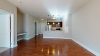 This single-floor residence is designed with a practical, open-concept layout that connects the living and kitchen areas seamlessly. Rich hardwood-style flooring flows throughout the main living spaces, complementing the neutral gray wall tones and white trim that give the unit a clean, cohesive aesthetic.

The kitchen is positioned along a peninsula-style counter with granite-look countertops, providing both workspace and a casual dining ledge. Dark espresso cabinetry offers generous storage, while stainless steel appliances — including a refrigerator, range, and over-the-range microwave — add a modern finish. Pendant lighting suspended above the peninsula enhances both function and style.

The living area is bright and open, benefiting from natural light streaming through a sliding glass door that leads to a private balcony. The bedrooms feature soft wall-to-wall carpeting and windows that allow natural light to fill each room.

The bathroom is finished with large-format tile flooring, a tub-shower combination, and a vanity with granite-look countertops and dark cabinetry consistent with the kitchen's design language. Overall, the space offers a well-coordinated, move-in-ready environment with consistent finishes throughout.