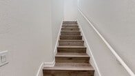 Located on Fenton Parkway in San Diego's Mission Valley area (92108), this two-story, one-bedroom, one-bathroom home is thoughtfully laid out across two levels. The ground floor houses a private garage with tile flooring, an automatic opener, and exposed beam ceiling details. A staircase connects to the main living level above, which comprises the majority of the home's total floor area.

The main level features light hardwood-style flooring throughout and is bathed in natural light from multiple windows, including a charming arched window and a set of French doors that open to an outdoor view. High ceilings in the living area enhance the sense of openness, complemented by a ceiling fan with light fixture.

The kitchen is well-appointed with white shaker-style cabinetry, granite-look countertops, and a full suite of stainless steel appliances including a gas range, microwave, dishwasher, and refrigerator. A sliding glass door in the kitchen area provides additional natural light and outdoor access.

The spacious primary bedroom features vaulted ceilings, a ceiling fan, and leads to a generous walk-in closet outfitted with built-in shelving and hanging rods. The bathroom is finished with a white vanity, granite-look countertop, and a full tub-shower combination.