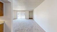 Located at 4498 N Cornelia Ave in Fresno, California, this 2-bedroom, 1-bathroom residence offers a functional, single-story layout with a clean, neutral aesthetic throughout. The open living room is generously proportioned, featuring plush carpet, a textured ceiling, and a sliding glass door that fills the space with natural light and provides access to a private balcony with outdoor views. A ceiling fan adds comfort to the living area where wood-look flooring transitions from the carpeted zones. The galley-style kitchen is well-appointed with warm wood cabinetry lining both walls, ample counter space, a double-basin sink, and white appliances including a range and refrigerator. A skylight-style overhead fixture brightens the kitchen, which features easy-care wood-look flooring. Both bedrooms are carpeted and bathed in natural light from windows fitted with vertical blinds. Each bedroom includes a dedicated closet, with one featuring a walk-in closet for added storage. The full bathroom offers a single-sink vanity with wood cabinetry, a full tub-shower combination, and wood-look flooring. A hallway connects the living spaces efficiently, completing this well-organized and comfortable residential unit.