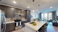 This single-story residence in Spring, Texas offers a thoughtfully designed open-concept layout that maximizes functionality and comfort. The kitchen serves as a central highlight, featuring dark gray shaker-style cabinetry that extends to the ceiling for ample storage, white quartz countertops, a tile backsplash, and a full suite of stainless steel appliances including a gas range, built-in microwave, and French door refrigerator. A kitchen island with an undermount sink and pendant lighting above provides additional prep space and casual seating, flowing seamlessly into the dining and living areas. The living room is bright and inviting, with wood-style flooring, a ceiling fan, and French doors that open to a private balcony with outdoor views. The bedroom is carpeted for comfort, features a ceiling fan, and is served by a natural light-filled window. The full bathroom includes a soaking tub and shower combination with subway tile surround, wood-look tile flooring, and a dark vanity with countertop storage. Recessed lighting throughout the home contributes to a clean, modern aesthetic.