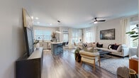 Located at 1115 S Mint St in Charlotte's vibrant South End neighborhood, this single-floor residence offers a thoughtfully designed open-concept layout with modern finishes throughout. Wide-plank hardwood-style flooring flows seamlessly from the living and dining areas into the kitchen, creating a cohesive and inviting atmosphere. Large windows fitted with blinds and sheer curtains fill the space with abundant natural light, while ceiling fans add both function and style.

The kitchen is a standout feature, showcasing gray shaker-style cabinetry, stainless steel appliances, a subway tile backsplash, and a generous island with a white quartz countertop and bar seating — ideal for casual dining or entertaining. A linear pendant light anchors the island with a sleek, contemporary touch.

The expansive living area comfortably accommodates generous seating arrangements and benefits from multiple windows that brighten the room. The bedrooms are well-proportioned, each featuring large windows, wood-look flooring, and ample natural light. One bedroom includes built-in shelving, adding practical storage and character.

The bathrooms are finished with gray vanity cabinetry, black hardware accents, and wood-look tile flooring. The primary bath features a glass-enclosed walk-in shower and access to a walk-in closet, completing this polished and functional residence.