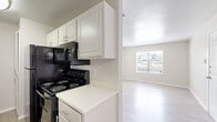 This single-story, one-bedroom, one-bathroom residence offers a practical and comfortable layout designed for efficient living. The interior is finished with a consistent neutral color palette of warm beige and white tones, creating a bright and cohesive atmosphere throughout.

The living area greets you at entry through a classic six-panel white door, with a window fitted with horizontal blinds that allows natural light to fill the space. Light-toned laminate flooring runs through the main living areas and kitchen, adding a clean, modern touch.

The galley-style kitchen is well-equipped, featuring white cabinetry with brushed nickel hardware, white quartz countertops, a stainless steel sink with a modern pull-down faucet, and black appliances including an electric range, microwave, and refrigerator. A textured backsplash adds a subtle design element.

The bedroom is comfortably sized, carpeted for warmth, and includes a window overlooking outdoor greenery, offering a peaceful, natural view. It provides direct access to a dedicated closet featuring dual hanging rods and built-in shelving, offering generous storage capacity.

The bathroom is clean and functional, featuring a full-size tub-shower combination with a curved curtain rod, a toilet, and light wood-look flooring that ties in with the rest of the unit. Textured ceilings are present throughout, adding a classic residential character to the space.