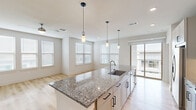 Located in Round Rock, TX, this well-designed single-story home offers three bedrooms, three bathrooms, and three closets within a thoughtfully laid-out floor plan. The open-concept kitchen and living area serves as the heart of the home, centered around a large granite island with a undermount sink and striking pendant lighting. White shaker cabinetry, stainless steel appliances, and light hardwood-style flooring complete the kitchen's modern aesthetic. The living area is bathed in natural light from multiple windows with clean white blinds, and a sliding glass door opens to a private balcony, extending the living space outdoors. A dedicated mudroom entry features built-in shelving, hooks, and a granite-topped bench, adding everyday functionality. The bedrooms are carpeted for comfort, each equipped with a ceiling fan and natural light. The spacious primary bedroom includes a walk-in closet outfitted with ample shelving and hanging rods. The bathrooms are finished with granite vanities, white cabinetry with matte black hardware, and tiled tub-shower combinations. Throughout, a neutral color palette, recessed lighting, and consistent finishes create a cohesive and modern living environment.
