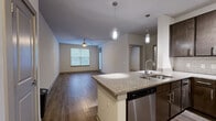 Located at 645 Old Hickory Boulevard in Nashville, Tennessee, this one-bedroom, one-bathroom residence offers a well-designed layout across a single floor. The open-concept living and kitchen area forms the heart of the home, where rich hardwood-style flooring flows throughout. The living room is bright and welcoming, featuring a ceiling fan, a large window, and a glass-panel door that fills the space with natural light.

The kitchen is a functional highlight, showcasing dark espresso cabinetry with brushed nickel hardware, granite countertops, a subway tile backsplash, and a full suite of stainless steel appliances including a refrigerator, range, microwave, and dishwasher. A peninsula with pendant lighting provides additional prep space and a natural divide between the kitchen and living area.

The bedroom offers a comfortable, carpeted retreat with a ceiling fan and a window allowing natural light. An adjacent closet provides dedicated storage. The bathroom features a granite-topped vanity with dark wood cabinetry, a large mirror, and a tiled shower, maintaining the consistent, modern aesthetic found throughout the residence. The entryway is clean and practical, with additional cabinetry overhead for extra storage. Overall, the space presents a cohesive, contemporary design with quality finishes throughout.