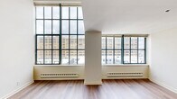 Located at 317 North Broad Street in the heart of Philadelphia, this two-story, one-bedroom, two-bathroom residence offers a thoughtfully designed layout spread across two levels. The main floor opens through a hallway into a spacious living area distinguished by dramatic floor-to-ceiling steel-framed windows that flood the space with natural light and frame sweeping views of the Philadelphia skyline. Hardwood flooring runs throughout the living area, complementing the bright, neutral palette of the walls. The kitchen features rich cherry wood cabinetry, dark granite countertops, tile flooring, and a full suite of stainless steel appliances, including a range, microwave, dishwasher, and refrigerator. A convenient pass-through connects the kitchen to the living area. The main level also includes a bathroom with a granite vanity countertop and a large mirror. A staircase leads to the upper level, where the primary bedroom offers plush carpeting, a large window with urban views, tall ceilings, and direct access to a private en-suite bathroom. A second, smaller carpeted room on the upper level provides added flexibility. The residence combines industrial architectural character with modern finishes throughout.