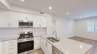 Located at 39261 Delhaven Street in Murrieta, California, this single-story, 2-bedroom, 2-bathroom home offers a thoughtfully designed layout with modern finishes throughout. The open kitchen and living area serves as the heart of the home, showcasing crisp white shaker cabinetry, a classic subway tile backsplash, quartz countertops, a stainless steel double-basin sink, and a full suite of stainless steel appliances including a gas range, over-the-range microwave, dishwasher, and refrigerator. Light wood-style flooring flows through the main living areas, adding warmth and continuity. The bedrooms are carpeted for comfort, with the primary bedroom offering a dedicated en-suite bathroom and a walk-in closet with built-in shelving and hanging rods. A second well-sized bedroom features a bright window with natural light. Both bathrooms are finished with quartz countertops, wood-look flooring, and clean white fixtures; one includes a shower-tub combination with a window above. A hallway connects the bedrooms, and each room benefits from recessed lighting and window blinds. The overall aesthetic is clean, bright, and move-in ready, reflecting a modern and functional design sensibility.
