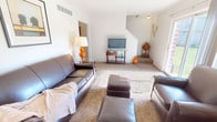 This two-story, 3-bedroom, 1.5-bathroom home delivers a practical and comfortable layout designed for everyday living. The main level features a carpeted living room bathed in natural light from a large sliding glass door that opens directly to a rear patio — an inviting outdoor space overlooking a well-maintained shared lawn. The living room offers generous space for seating arrangements and flows naturally through the home. The kitchen is outfitted with warm honey-toned wood cabinetry, ample counter space, and a gas range, providing a functional cooking environment. A half bathroom and a connecting hallway with tile flooring complete the main level. Upstairs, three bedrooms provide comfortable retreats, each with carpet flooring and windows that allow natural light to fill the rooms. The primary bedroom is well-sized, while the additional bedrooms offer versatility for family, guests, or a home office. The full bathroom on the upper level includes a tub-shower combination with tile surround. Throughout the home, a neutral color palette of white walls and light tones creates a clean, move-in-ready atmosphere. With a private patio, green outdoor surroundings, and a well-organized two-floor plan, this home provides a balanced blend of indoor comfort and outdoor accessibility.