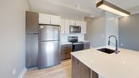 This thoughtfully designed 2-bedroom, 2-bathroom residence offers a functional and modern living experience across a single floor. The contemporary kitchen is a standout feature, equipped with stainless steel appliances including a full-size refrigerator, electric range, and built-in microwave. Two-toned cabinetry — combining dark wood lower cabinets with light upper cabinets — is complemented by a white subway tile backsplash, light quartz countertops, and light hardwood-style flooring that extends into the main living areas.

A central hallway connects the main spaces efficiently, with recessed lighting maintaining a clean, modern aesthetic throughout. Both bedrooms are carpeted with a patterned multi-tone carpet and feature ceiling fans and windows that frame urban city views. The primary bathroom is elegantly appointed with a long dark wood vanity, dual sinks, an illuminated mirror, wood-look tile flooring, and a glass-enclosed walk-in shower. The secondary bathroom offers a clean, minimalist design with a soaking tub and glass shower enclosure with matte black hardware accents. A dedicated closet provides additional storage, rounding out this well-appointed and move-in-ready residence.