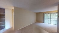 Located at 1300 S Eagle Ridge Dr in Renton, Washington, this single-floor unit offers a practical and well-organized layout with a neutral, warm color palette throughout. The expansive living area is finished with plush wall-to-wall carpet and a textured ceiling, creating a comfortable and inviting atmosphere. Sliding glass doors allow natural light to pour in and provide access to an outdoor space, enhancing the openness of the main living area.

The galley-style kitchen features light wood flooring, white cabinetry, laminate countertops, and a full suite of black appliances including an electric range, dishwasher, and refrigerator. Track lighting overhead keeps the kitchen well-lit and functional.

The bedrooms are generously sized, each with soft carpet, warm-toned walls, and baseboard heating. Large windows in each bedroom bring in natural light and offer pleasant outdoor views of the surrounding greenery and building exterior.

Two bathrooms serve the unit. The full bathroom includes a soaking tub and shower combination with a white surround, a single-sink vanity with a lighted mirror, and wood-style flooring. The second bathroom features a tub/shower combo and wood-style flooring as well. Clean, simple finishes throughout give the unit a move-in-ready appeal.