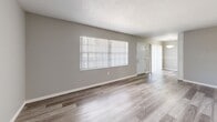 Located at 2002 Colonial Parc Dr in Tampa, FL, this two-bedroom, one-bathroom residence offers a thoughtfully laid-out single-floor plan. Consistent wood-look flooring flows throughout, complemented by neutral gray walls, white baseboards, and textured ceilings that lend a clean, cohesive aesthetic.

The open kitchen and living area form the heart of the home. The kitchen is equipped with white cabinetry, granite-look countertops, a double-basin sink with a brushed gold faucet, and stainless steel appliances including a refrigerator and electric range. The adjacent living room benefits from a large window that fills the space with natural light, while a sliding glass door opens to a private balcony overlooking the surrounding landscape.

The spacious primary bedroom provides generous room and includes a closet with panel doors. The second bedroom also features wood-look flooring, a window for natural light, and its own closet. A hallway connects the bedrooms to the full bathroom, which includes a tiled tub-shower combination, a white vanity, and wood-look flooring that mirrors the rest of the home. The layout is completed by a dedicated hallway with additional storage access, making this residence both functional and inviting.
