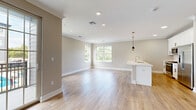Located at 445 South Ave E in Westfield, NJ, this thoughtfully designed 1-bedroom, 1-bathroom residence offers a well-appointed single-floor layout with generous living space. Light hardwood flooring flows seamlessly throughout, complemented by neutral warm-beige walls and crisp white trim, creating a bright and cohesive aesthetic.

The heart of the home is an expansive open-concept living, dining, and kitchen area filled with natural light from multiple windows that frame lush greenery views. The kitchen features white shaker cabinetry, a large peninsula with white quartz countertops, stainless steel appliances including a refrigerator and microwave, and elegant gold pendant lighting overhead. Sliding glass doors lead to a private balcony, extending the living area outdoors.

The spacious bedroom is a serene retreat with a large window, recessed lighting, and wood flooring. It is accompanied by three well-organized closets with built-in shelving, offering exceptional storage. A dedicated laundry area adds everyday convenience.

The bathroom is finished to a high standard, featuring marble-look tile flooring, a soaking tub with a marble-surround shower, a white vanity with quartz countertop, and a large mirror with bright vanity lighting. Crown molding and recessed lighting throughout add refined architectural detail to this polished Westfield residence.