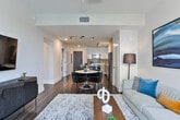 Located in the heart of Atlanta's prestigious Buckhead district, this single-floor residence at 3372 Peachtree Rd NE offers a refined blend of contemporary design and urban sophistication. The open-concept kitchen is a standout feature, outfitted with high-gloss white upper cabinetry, warm wood-tone lower cabinets, a tasteful subway tile backsplash, and a full suite of stainless steel appliances including a French door refrigerator, electric range, built-in microwave, and dishwasher. A large white quartz island with bar seating serves as both a functional workspace and a social hub connecting the kitchen to the dining and living areas. The living room is bathed in natural light from expansive floor-to-ceiling sliding glass doors that open to a balcony, framing sweeping views of the Atlanta skyline and surrounding greenery. Rich hardwood flooring runs throughout the main living spaces, adding warmth to the modern aesthetic. The bedroom offers a tranquil retreat with plush carpeting and tasteful wall art. The bathroom is elegantly appointed with marble-look tile surrounding a deep soaking tub and glass-enclosed shower. Throughout the space, a cohesive palette of neutral tones, modern finishes, and curated design details creates a polished, contemporary atmosphere ideal for upscale urban living.