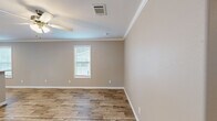 Located at 9101 Normandy Boulevard in Jacksonville, FL, this single-story, 3-bedroom, 2-bathroom home offers a clean, modern aesthetic throughout. The interior is unified by warm wood-look luxury vinyl plank flooring and neutral taupe-toned walls, complemented by crisp white crown molding and baseboards that add a polished finish to every room.

The heart of the home is an open-concept living, dining, and kitchen area. The kitchen is well-equipped with white shaker-style cabinetry, white countertops, stainless steel appliances including a side-by-side refrigerator, dishwasher, and range, plus a pantry for additional storage. Recessed lighting and a window above the sink keep the space bright and functional. A breakfast bar provides a natural transition into the dining and living areas, which feature ceiling fans and windows dressed with white blinds.

The three bedrooms are comfortably sized, each with crown molding, ceiling fans or light fixtures, and natural light from windows. The primary bedroom includes an en-suite bathroom with a vanity, sliding glass shower enclosure, and wood-look flooring. The second bathroom features a full tub-shower combination with clean white surround. Additional highlights include four closets, a dedicated laundry area, a hallway, and a welcoming entrance, making this home highly functional and move-in ready.